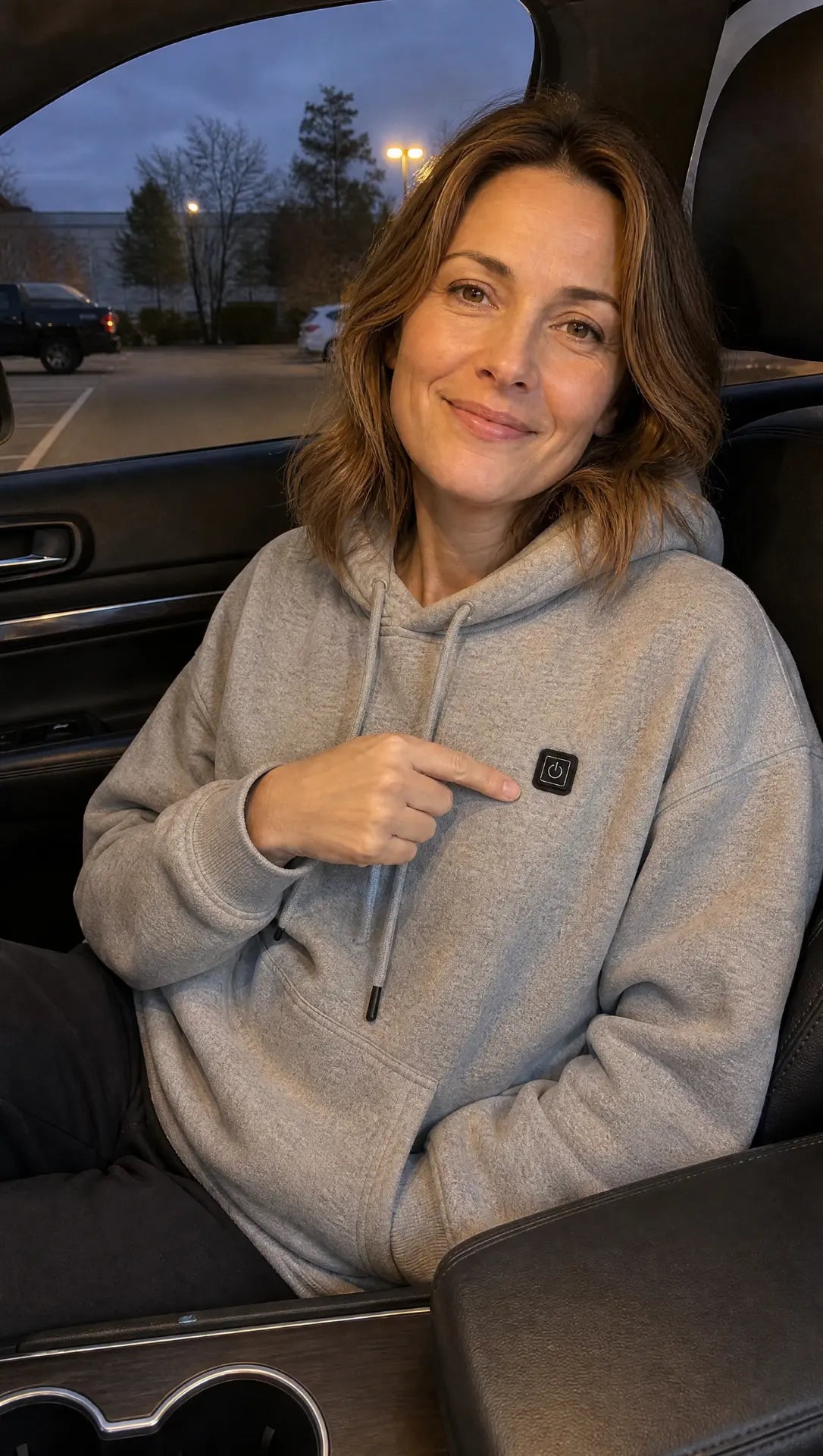 Woman using the Grey EmberNest Heated Hoodie in a car